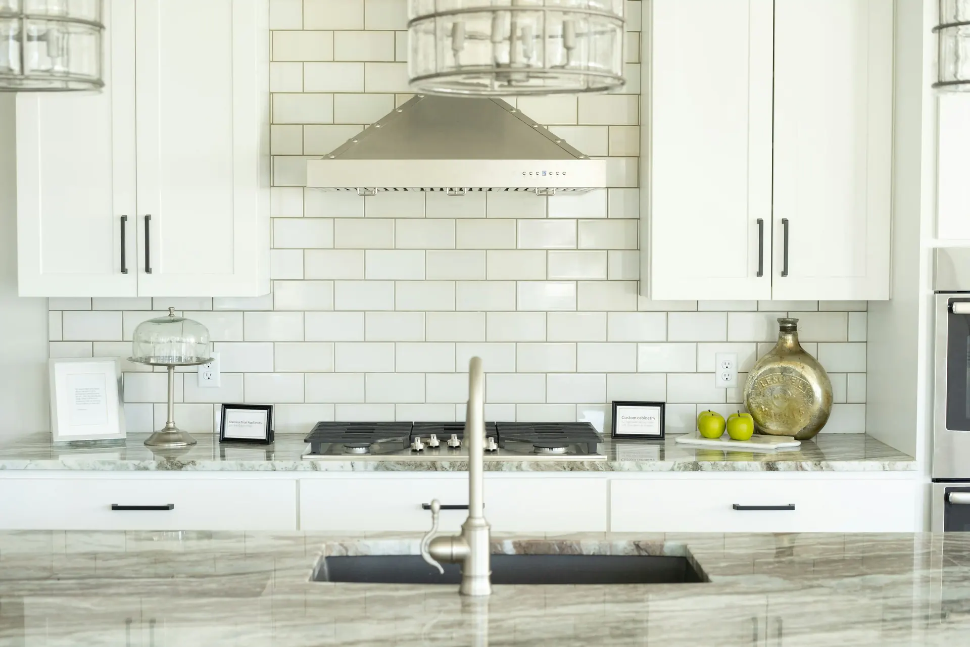 White kitchen with a white subway tile backsplash and marble counters